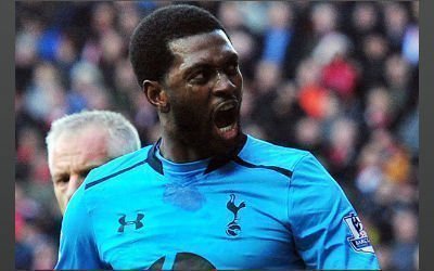 Emmanuel Adebayor celebrates scoring for Spurs as the referee looks on.