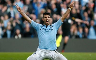 Sergio Aguero slides on his knees with both hands in the air to celebrate scoring for Manchester City